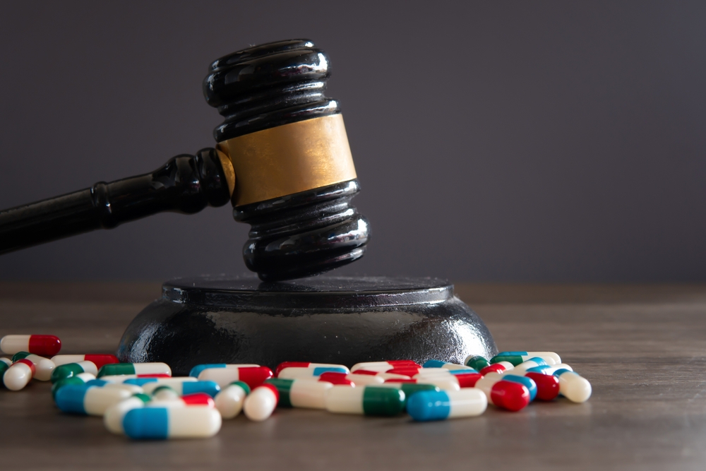 Closeup image of colorful medicine pills and judge gavel on table.